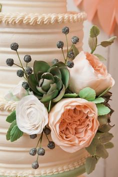 a wedding cake decorated with flowers and succulents