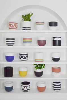 a white shelf filled with lots of different colored cups