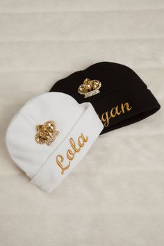 two black and white beanies with gold crowns on them, one is personalized