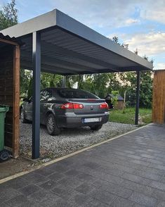 a car is parked in the gravel under a carport with a roof over it