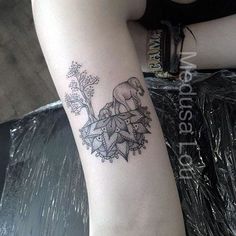 an elephant tattoo on the arm of a woman's left leg, with leaves and flowers around it