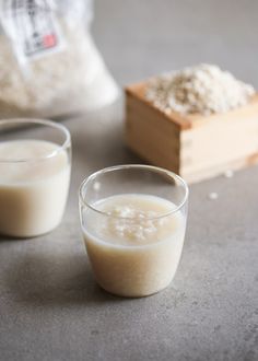 two glasses filled with liquid sitting on top of a table next to a bag of rice