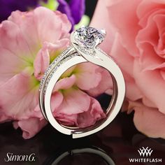 a diamond ring sitting on top of a table next to pink flowers and peonies