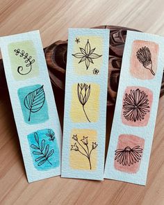 four bookmarks with flowers and leaves on them sitting on a wooden table next to a car