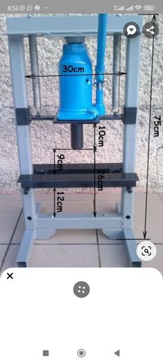 a blue machine sitting on top of a white table next to a wall with measurements