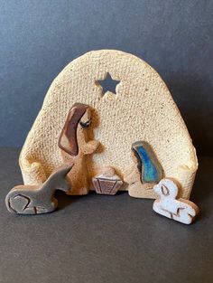 a small nativity scene made out of clay on a black surface with stars in the background