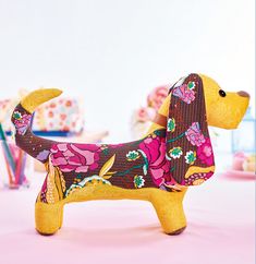 a dog made out of fabric sitting on top of a pink tablecloth covered table