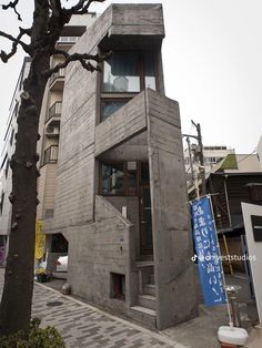 a building made out of concrete sitting next to a tree