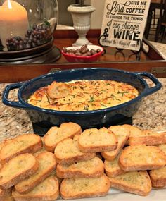 a blue dish filled with bread on top of a counter next to a pile of crackers