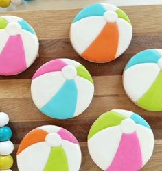 cupcakes decorated to look like beach balls on a wooden board with candies