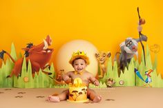 a baby sitting in front of a cake with animals on it and an egg behind him