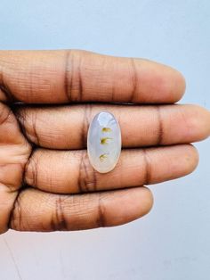 a person's hand holding a white and gold ring with small flowers on it