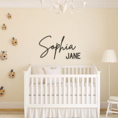 a white crib in front of a wall with the name sophia jane on it