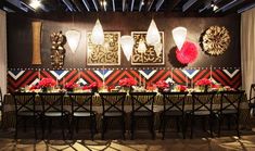 a long table with many chairs and vases on it in front of a wall decorated with art