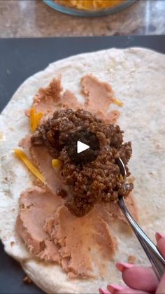 a tortilla being filled with meat and sauce