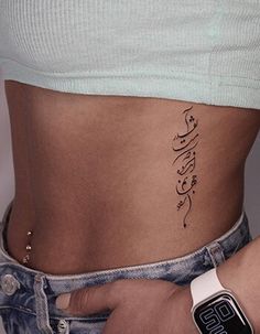 a woman's stomach with arabic writing on the side and an apple watch in her hand