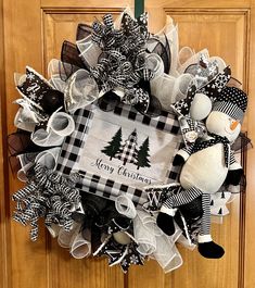 a christmas wreath on the front door with snowmen and trees in black and white