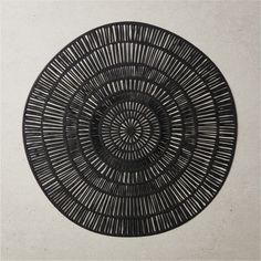 a black circular object on a white wall in the shape of a sunburst