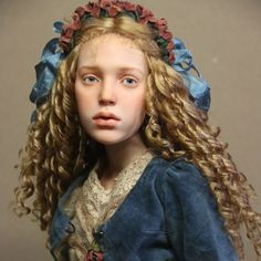 a doll with long blonde hair wearing a blue dress