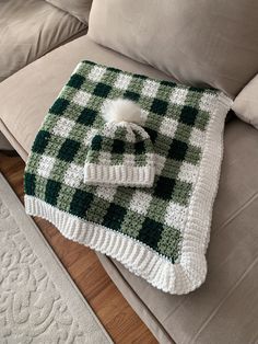 a green and white blanket sitting on top of a couch