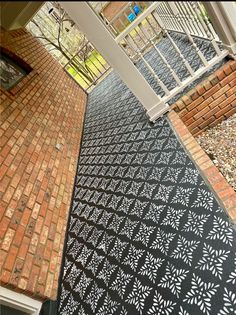 a black and white patterned walkway next to a brick building