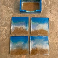 four pieces of blue and white glass with sand in the middle on a marble surface