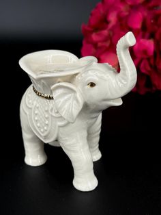 an elephant figurine holding a vase with its trunk