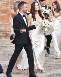 a man in a tuxedo is walking next to a woman in a white dress