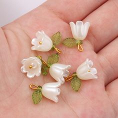 five white flowers with green leaves are sitting on someone's hand