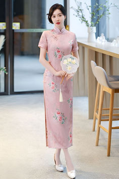 Long pink qipao dress with a Chinese floral motif and a mandarin collar Elegant Pink Dress With Stand Collar, Pink Short Sleeve Cheongsam For Spring, Pink Stand Collar Dresses For Spring, Pink Stand Collar Dress For Spring, Long Pink Feminine Dress, Pink Fitted Dress With Stand Collar, Fitted Pink Dress With Stand Collar, Pink Short Sleeve Ao Dai For Spring, Pink Fitted Cheongsam With Short Sleeves