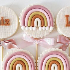 decorated cookies are arranged in the shape of rainbows with ribbons and letters on them