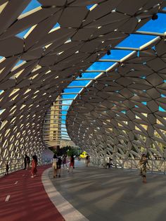 people are walking on the walkway in front of a large structure with white and red lines