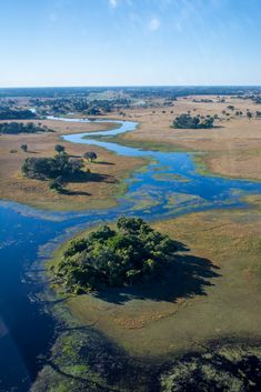 an aerial view of the water and land in the middle of the plains, with trees on either side