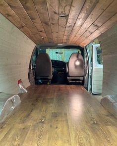 the interior of a van with wood flooring and white walls, including an open door