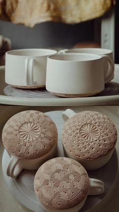 three white cups and saucers sitting on top of a plate next to each other