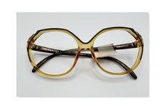 Deadstock Saphira Optyl eyeglass frames made in Austria. Amber colored frames with dark brown arms and trim along the front. Y Arms are marked Optyl Saphira, Frame Austria, 4079 20 54 15.  The original price tag of $75.00 is still taped to the arm. You can take these to your optometrist and have prescription lenses made or tinted sunglasses. Measure a pair of your current eyewear and compare it to the measurements below. Hinge to Hinge is 5" Lens Width 2 " Lens Height 1 3/4" Arms are 5 1/2" These are vintage new, unworn. Colored Frames, 4 Arms, Tinted Sunglasses, Eye Wear Glasses, Amber Color, Price Tag, Prescription Lenses, Eyeglasses Frames, Eyewear Sunglasses