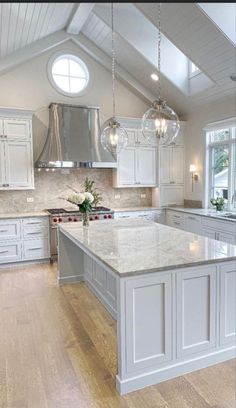 a large kitchen with an island in the middle of it and two chandeliers hanging from the ceiling