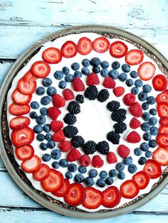 a cake decorated with strawberries, blueberries and raspberries in the shape of an o'clock