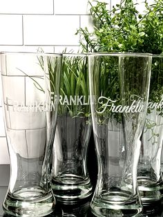 three clear glass vases with plants in them