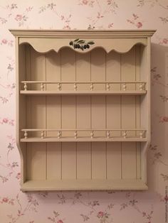 a white shelf sitting on top of a wall next to a flowered wallpaper