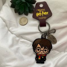 a harry potter keychain with a coin next to it on a white sheet