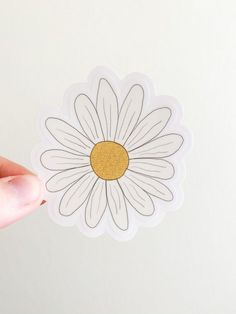 a person holding up a sticker with a flower on it's back side