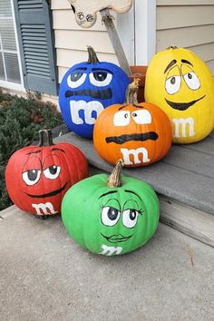 four pumpkins painted to look like faces on the front porch, with eyes drawn on them