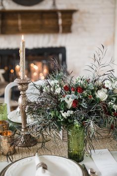 the table is set with candles and flowers in vases, plates and napkins