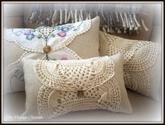 three decorative pillows on a white couch with lace and crochet trimmings