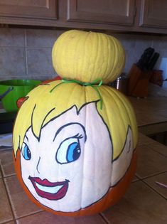 a pumpkin shaped like a cartoon character with blue eyes and blonde hair sitting on top of a kitchen counter