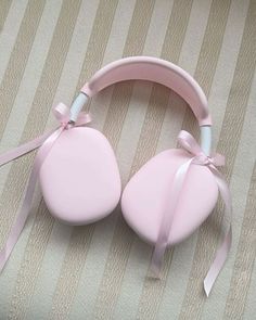 a pair of pink ear muffs tied with a ribbon on top of a bed