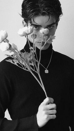 a young man holding flowers in his hands