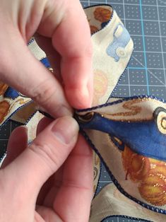 someone cutting fabric with scissors on top of a piece of cloth that is being sewn together