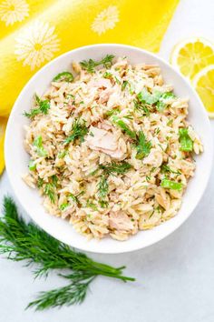 a white bowl filled with rice salad next to lemon wedges and a yellow towel